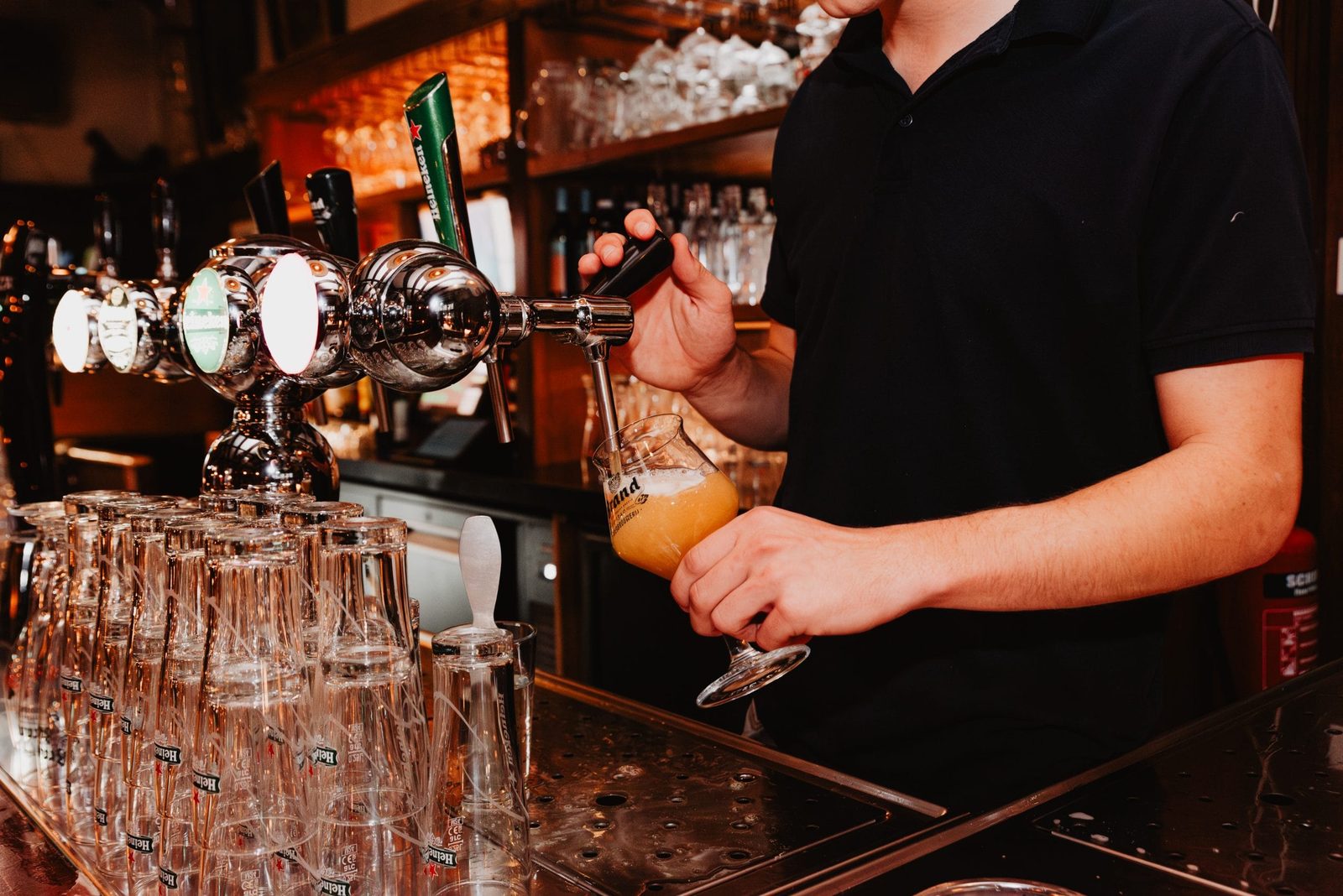 Barmedewerker tapt bier bij Stadtlander, met de tapinstallatie en biermerken op de achtergrond.